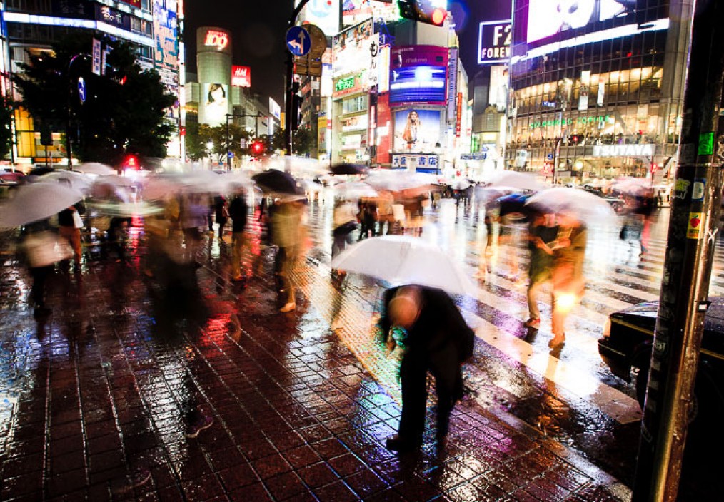 Blurred passengers cross at the shibuya corssing in tokyo in the rain